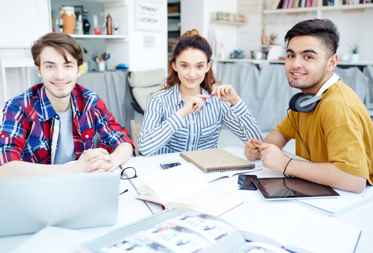 Three young professionals collaborating together at table with laptop