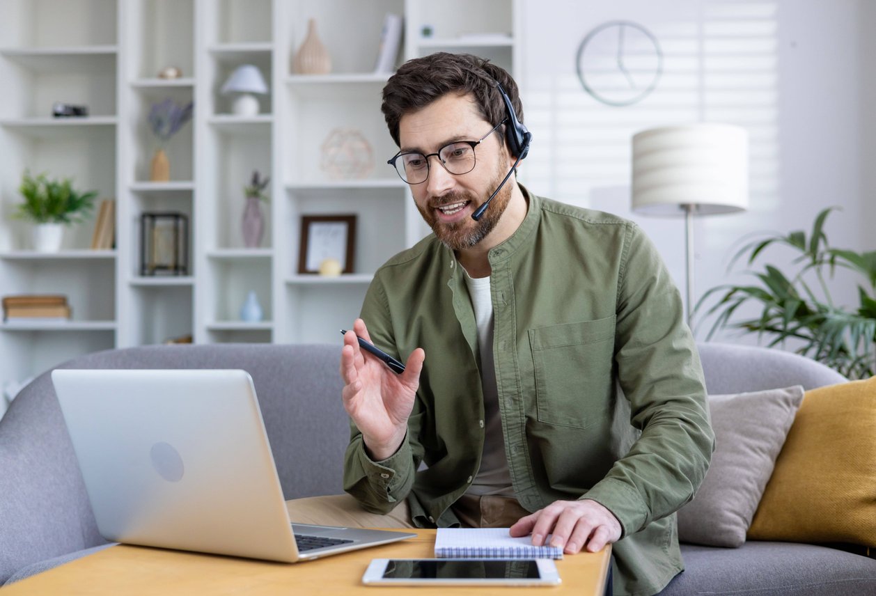 Man with headset and glasses speaking during virtual meeting at home