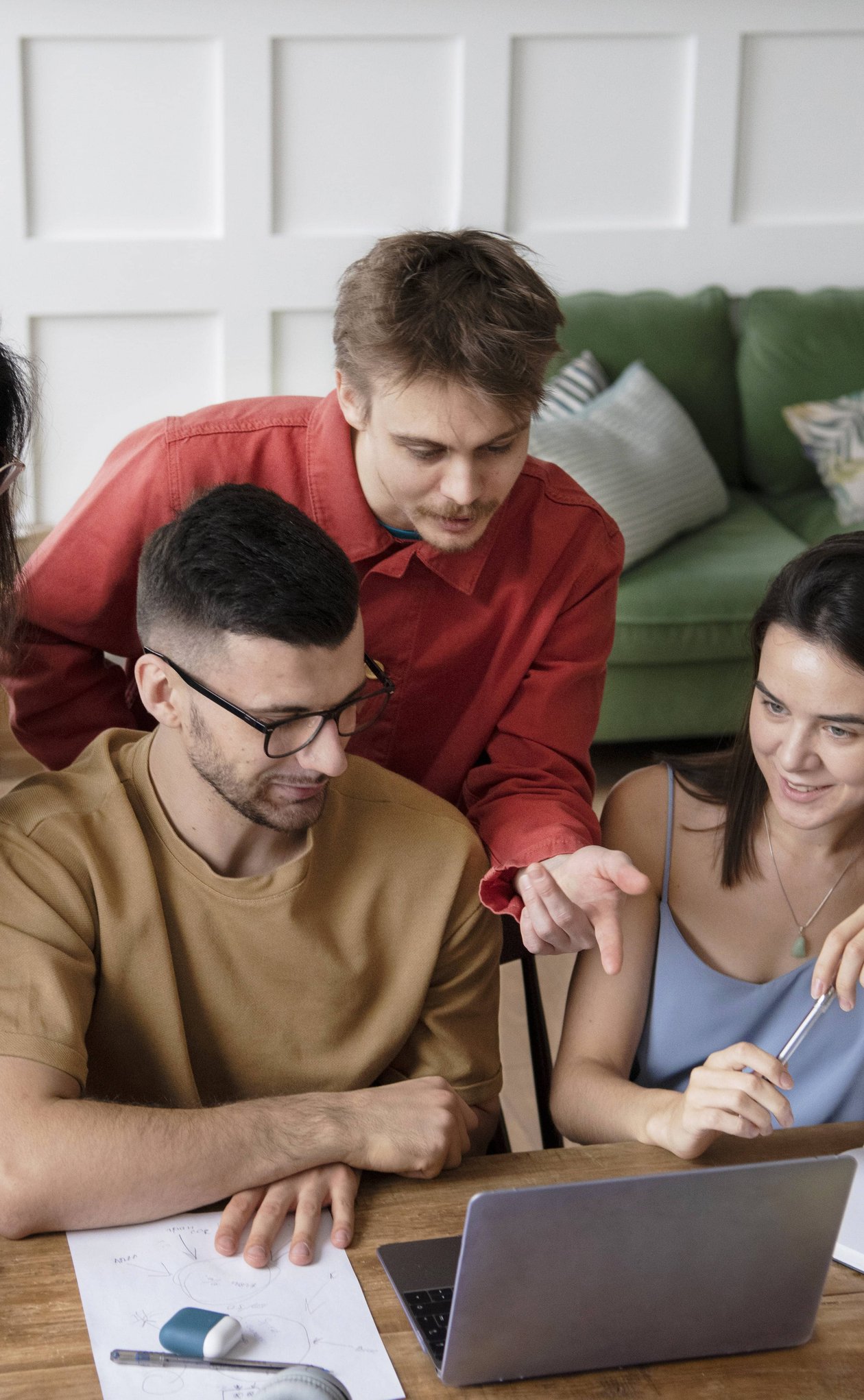 Diverse group gathered around laptop collaborating on project together